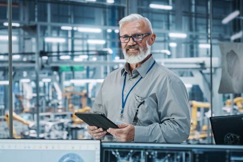 man in factory in a suit, holding an iPad