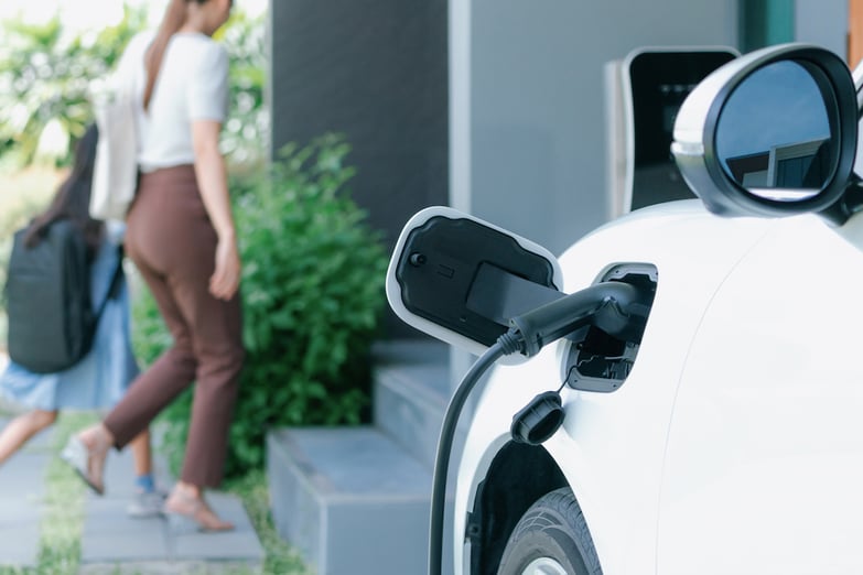 woman and child walking into their house with their electric car charging in front