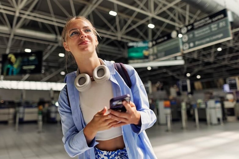 woman wearing headphones holding smartphone