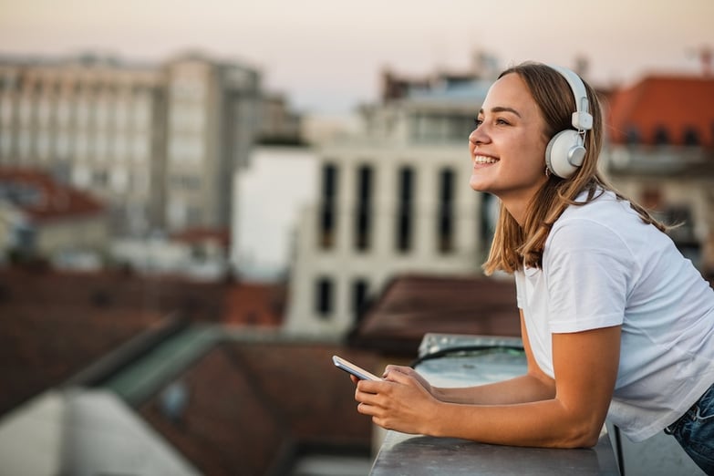 woman using bluetooth headphones on a terrace overlooking the city